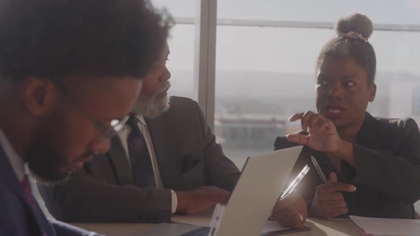 A group of black executives discussing at a table in an office during daytime