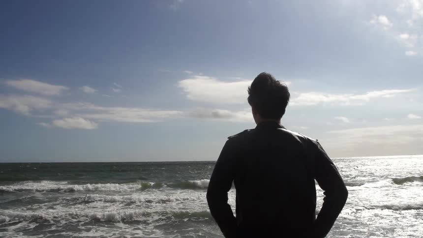 Man standing facing the ocean