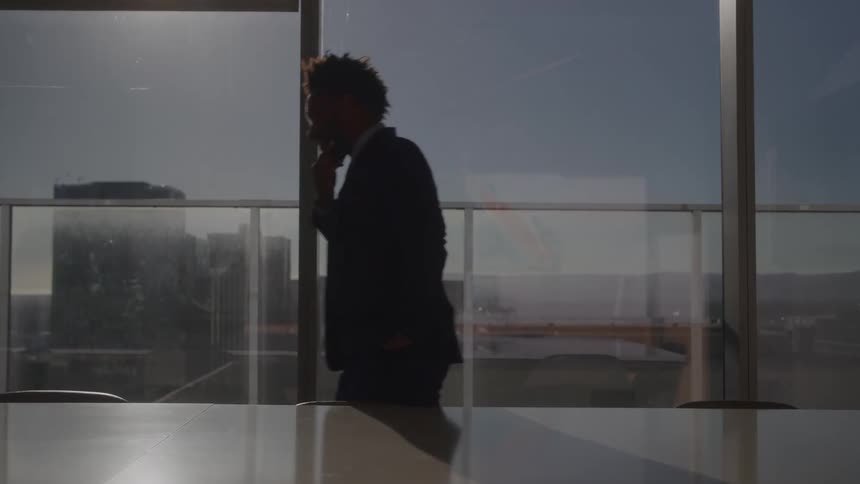 The man paces while thinking in the conference room