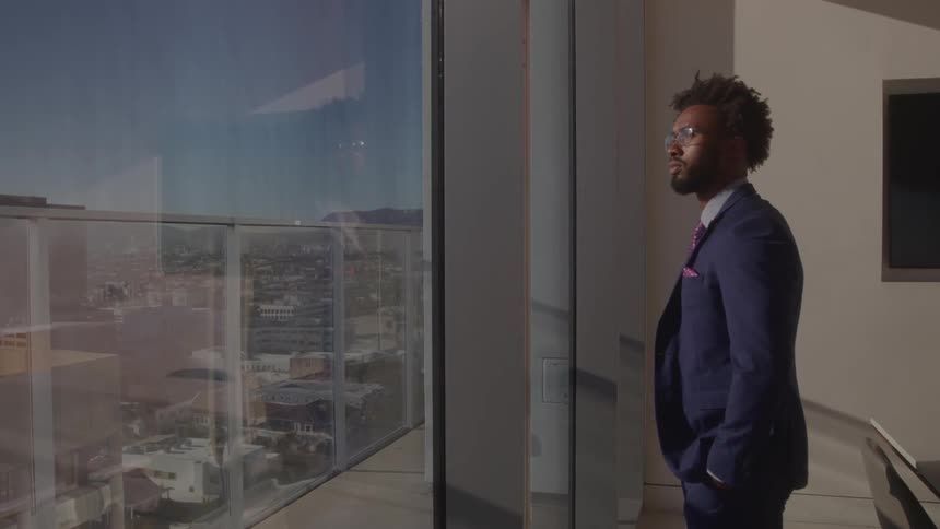 A man in a suit looks out a large window