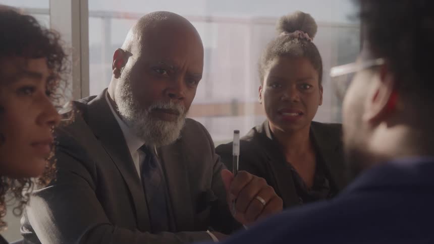 A group of people in business clothes sits around a table and talks
