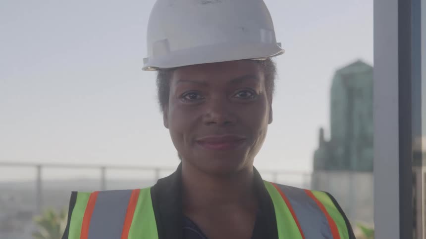 The construction worker is smiling brightly outside