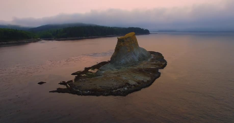 A rock formation island lies within a body of water