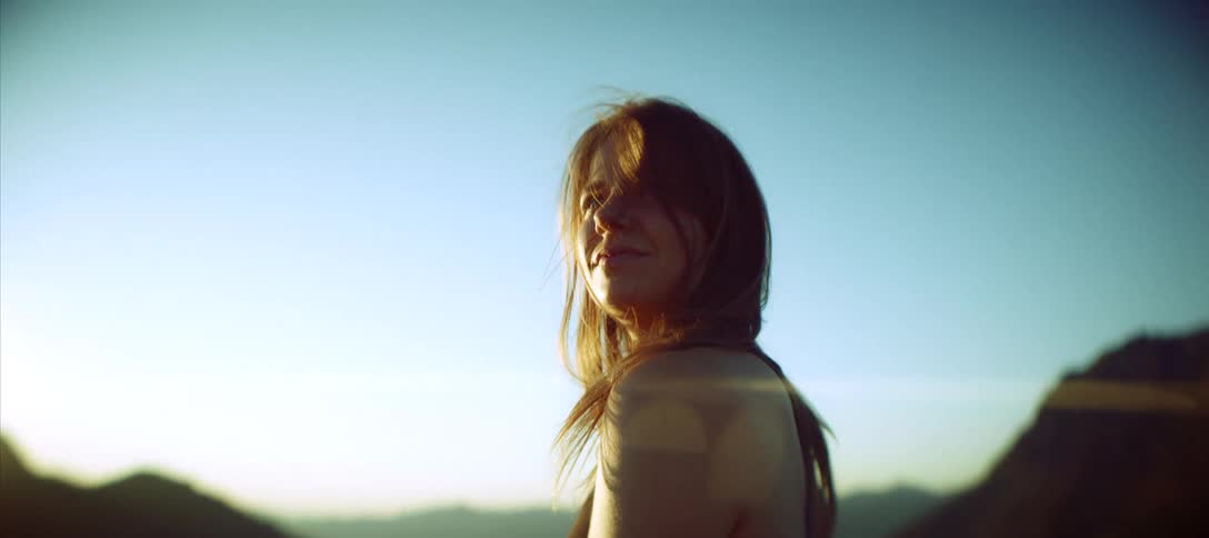 The woman smiles as she looks out over the mountains