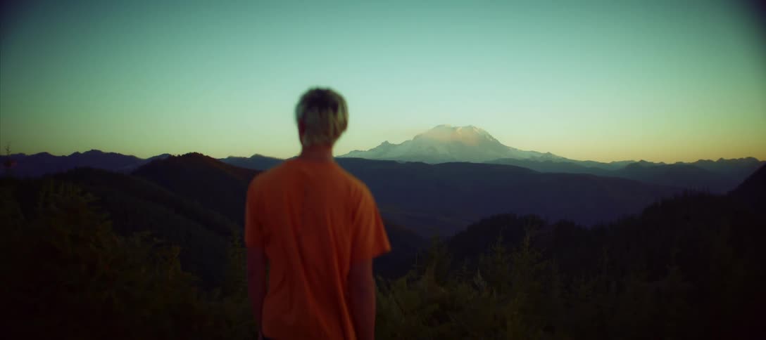 Man stands looking around foggy mountainous terrain