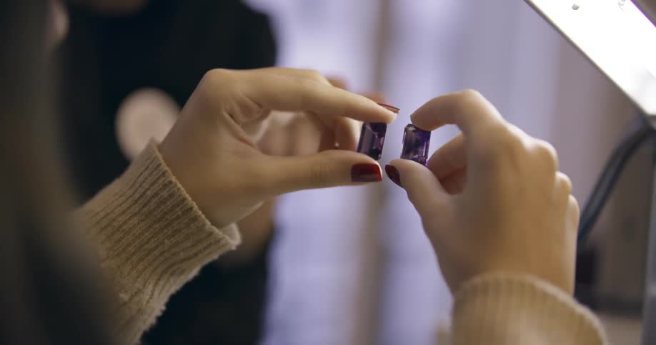 A person is examining two large purple jewels