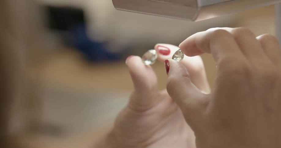 Woman holds and examines two diamonds