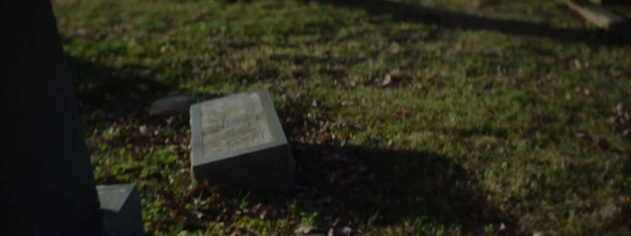 The video begins with a closeup on a gravestone showing the name alice mariah batey and the dates 18811972 the camera then slowly pans up and out revealing a wide shot of a solemn cemetery with many old tombstones scattered across a grassy tree