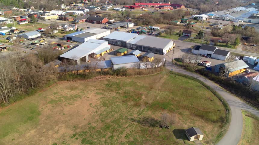 Aerial view of sheds and a suburb in an area with trees and grass