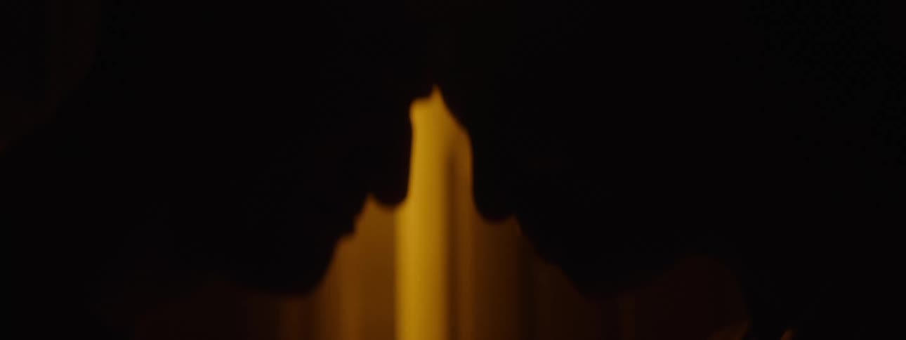 Silhouette of a couple in a dark room leaning their heads against each other
