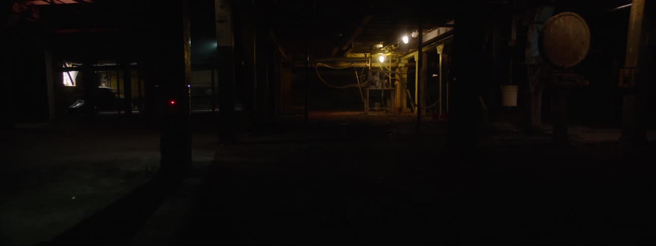 Person lights up the dark interior of a factory with a flashlight