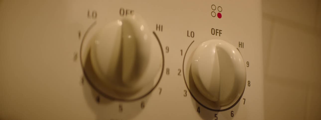 Close up of a person rotating a switch on an electrical appliance indoors