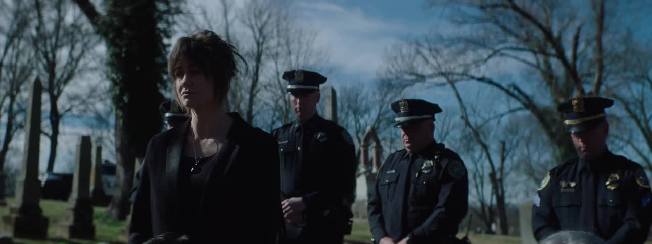 A group of people gathered at a cemetery for a burial during daytime