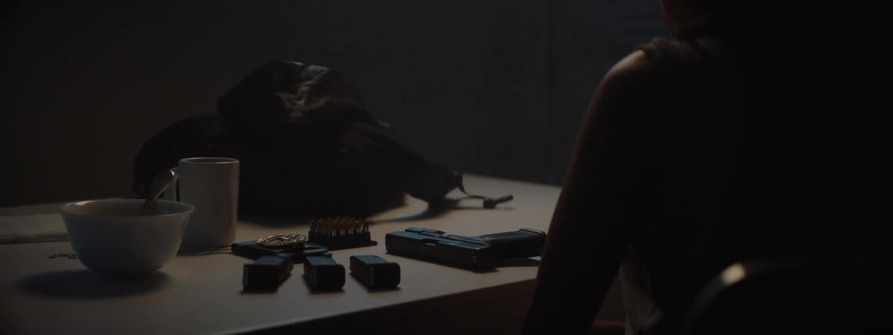 A female police officer sits at a table and inspects her firearm
