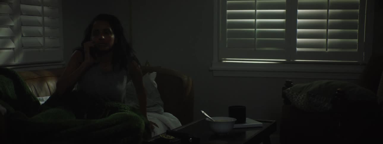 Woman lying down answering a phone call and getting up from the sofa