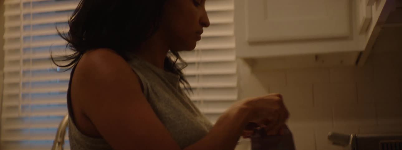 A young black woman preparing a beverage drink with an appliance in the kitchen at night