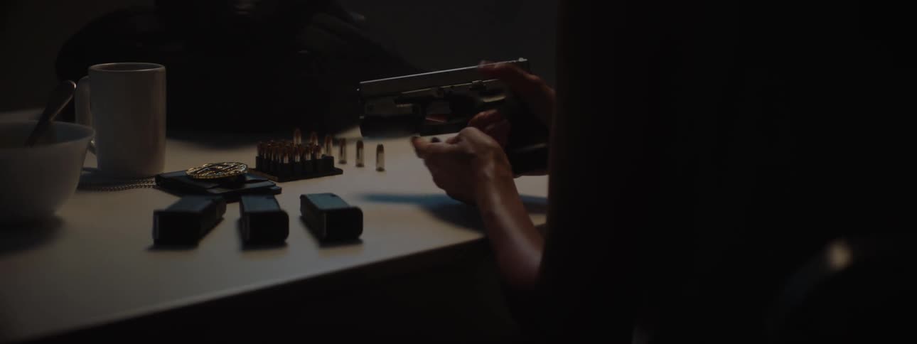 A female police officer sits at a table and inspects her firearm