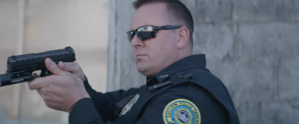 Close up of two police officers tactically approaching a building entrance with hand guns during daytime