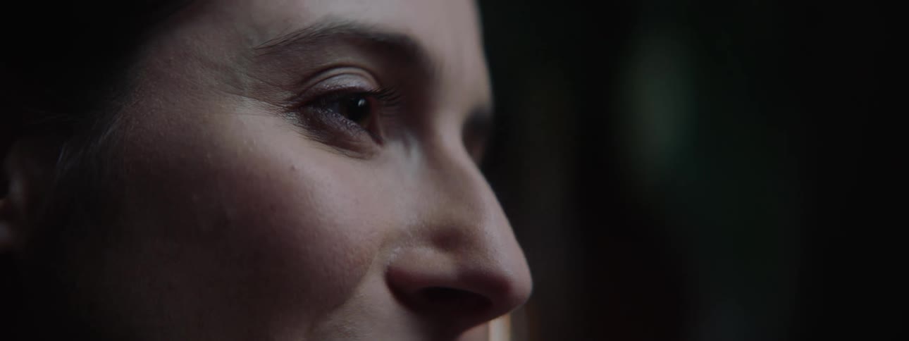 In an emotional close up a womans eye wells up with a tear as she breaks into a smile