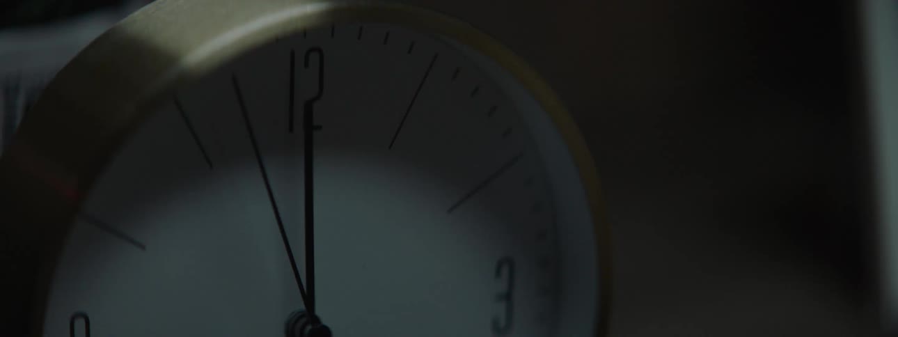 In a moody close up the second hand of a clock ticks past the twelve