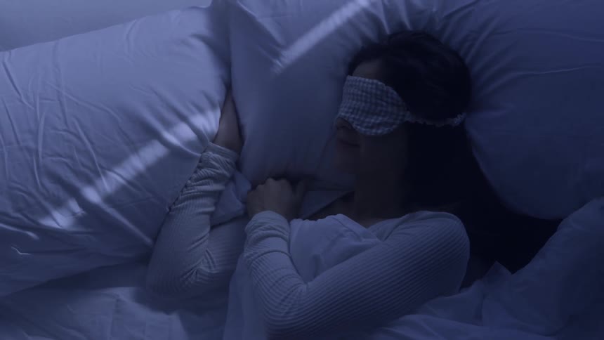 The woman is wearing a blindfold as she sleeps