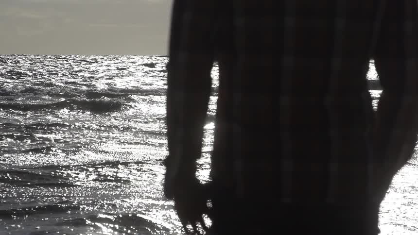 Person standing and looking out at the ocean waves