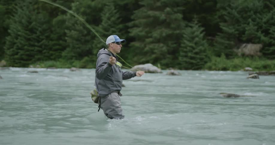 Man fishing in a shallow river using a fly fishing rod