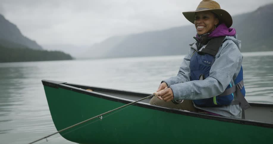 The woman sits in the boat fly fishing