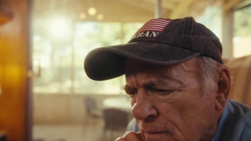 Elderly man looks intently at the phone screen in his hand