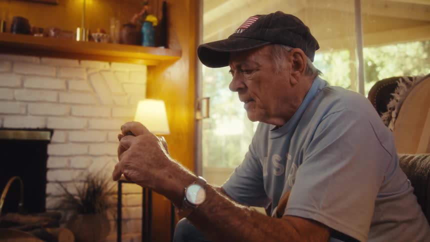 Elderly man in a cap interacting with a smartphone