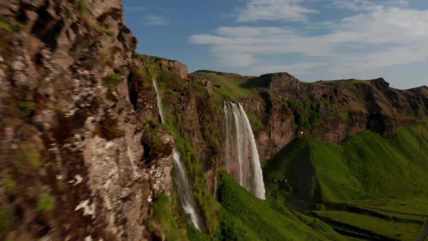 The majestic seljalandsfoss waterfall cascading down a vibrant green cliffside in iceland under a bright blue sky