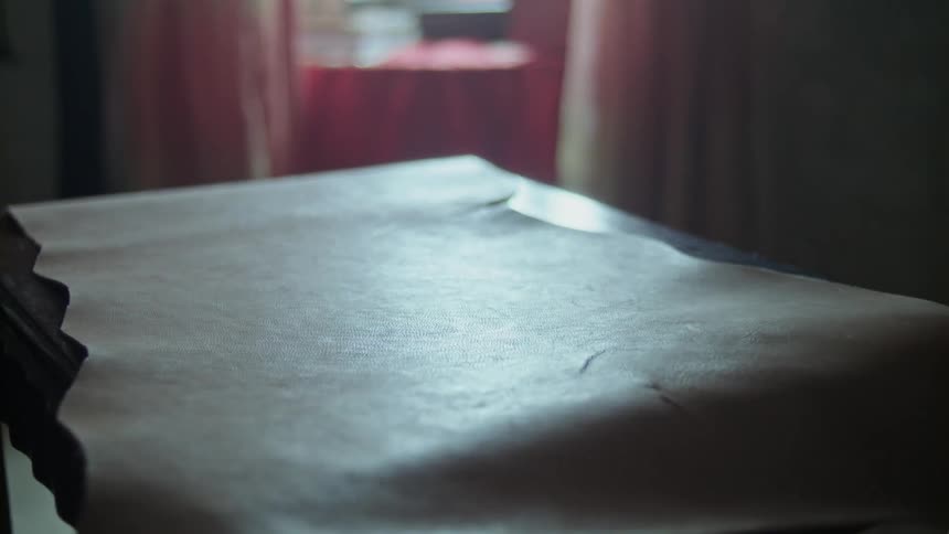 Person unrolling some paper on a small tabletop