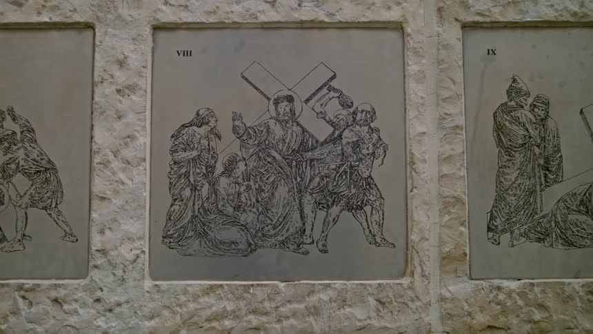 Old murals of religious men and jesus holding cross on a wall
