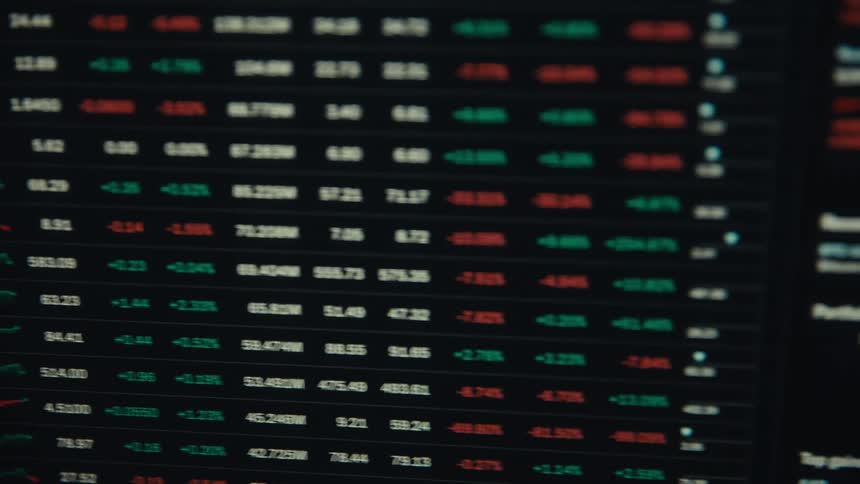 A dense slightly blurred market leaderboard of tickers and redgreen figures fills the screen