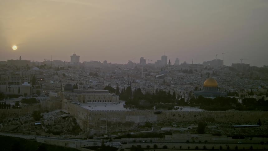 The sun is setting behind Jerusalem on a foggy day