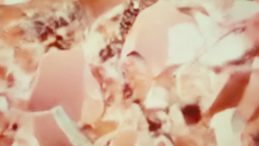 A pink ceramic piggy bank with a noticeable crack is shattered and the pieces explode downwards and outwards in a spray of fragments