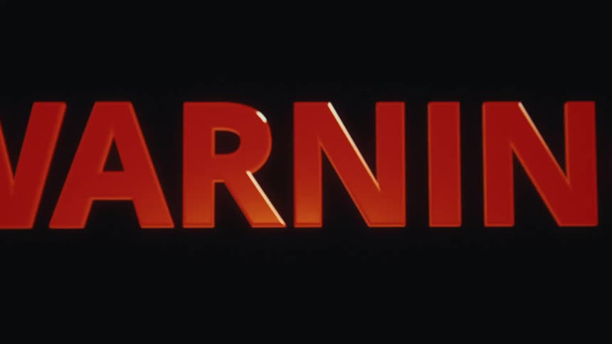 Huge backlit orange letters spell warning across a dark frame