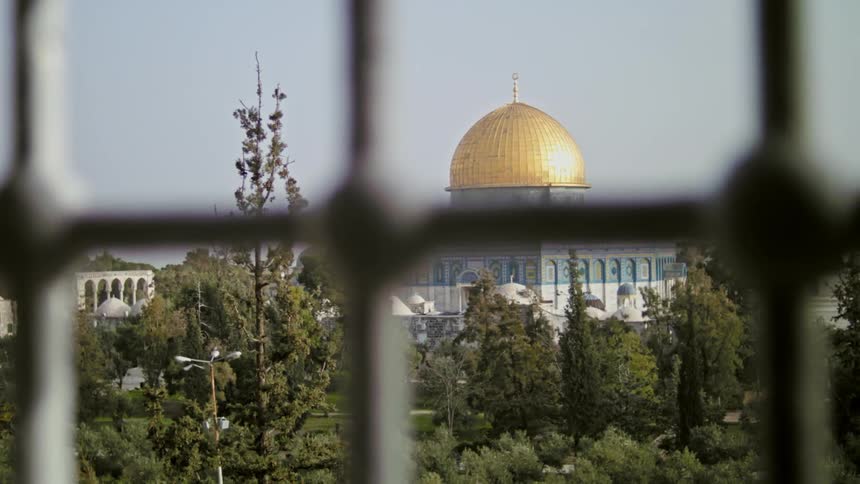 Building with golden dome is seen through metal bars