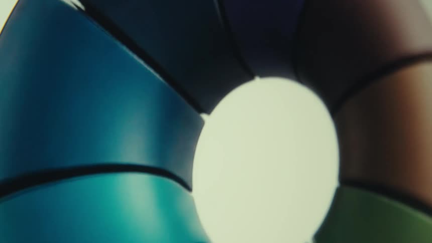 The first line shows a closeup of a rotating segmented object with a dark blue and teal color the second line shows the object continuing to rotate with each segment revealing a different color including shades of blue purple and green