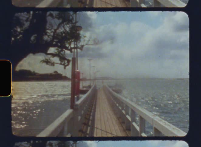 A wooden pier extends over water with visible sprockets on its edges
