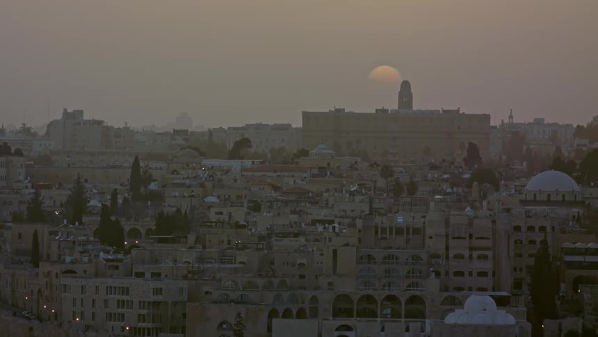The moon rises over a large city