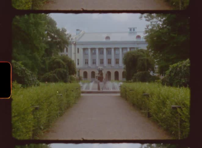 A pathway winds through a garden toward a large historic building