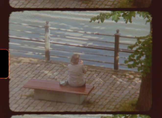 A man rides his bike past a woman sitting on a bench