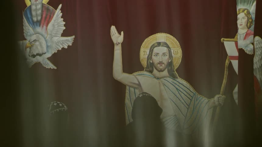 A mural of christ is painted on a curtain and then opened