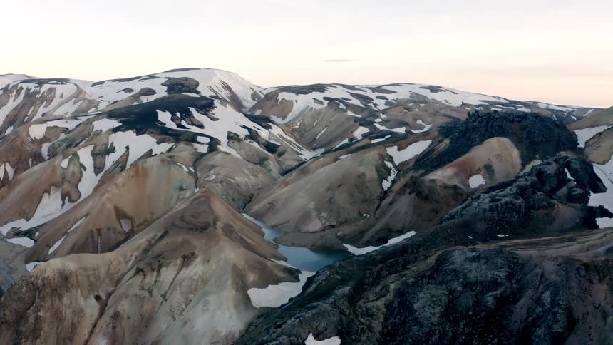 Rocky mountains with snow and a small lake in the valley