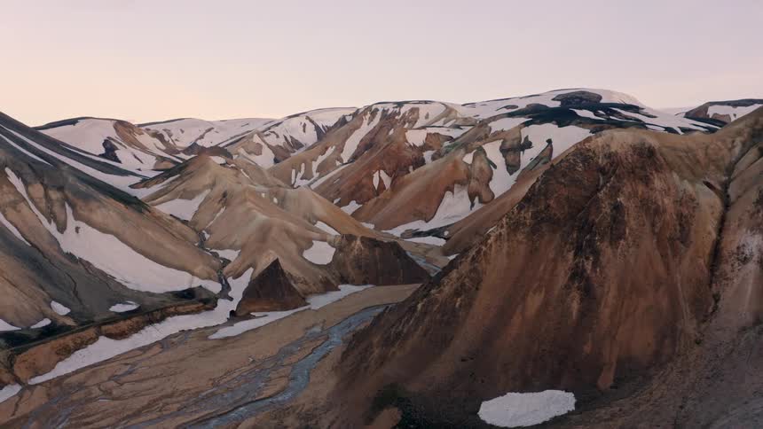 A mountain range in the wilderness partially covered in snow