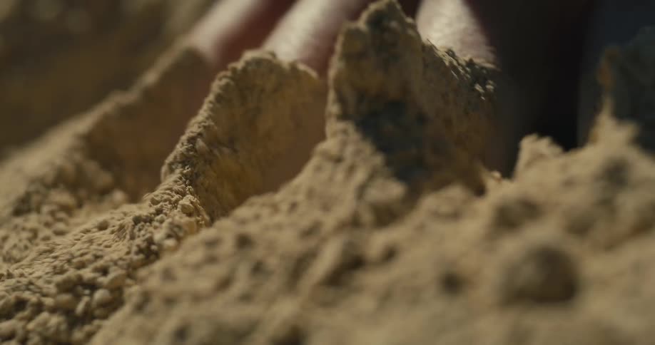 Fingers sinking and moving the sand in closeup