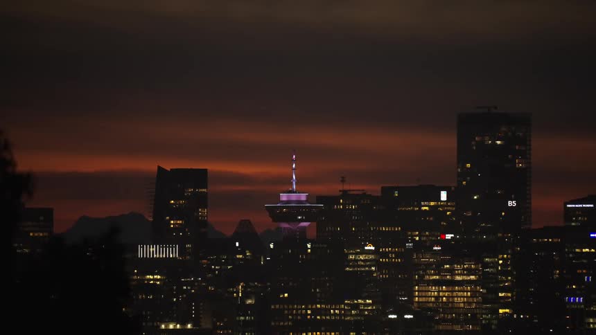 City skyline lit up at dusk with a central tower highlighted in purple tones