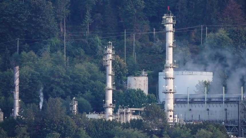Industrial towers and storage tanks surrounded by forest area