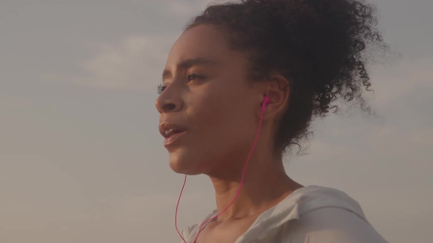 The woman listens to music on her earbuds outside